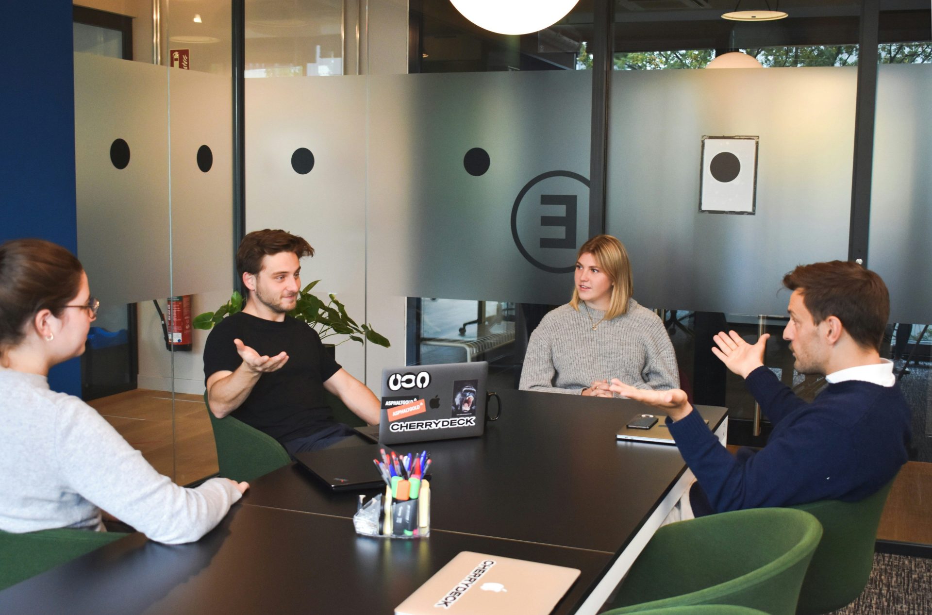 Vier Personen bei einer Besprechung an einem schwarzen Tisch in einem modernen Büro